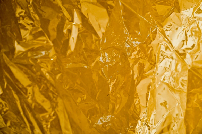 a piece of foil sitting on top of a table, inspired by Christo, unsplash, plasticien, yellow hue, dynamic closeup, caramel, detailed product image