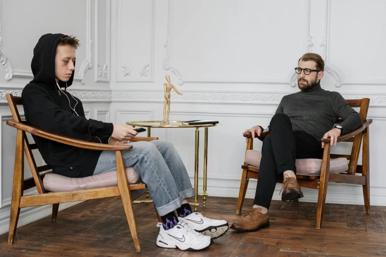 a man sitting in a chair next to a woman, by Nina Hamnett, pexels contest winner, rhett and link, neo rauch and nadav kander, conversation pit, daniil kudriavtsev