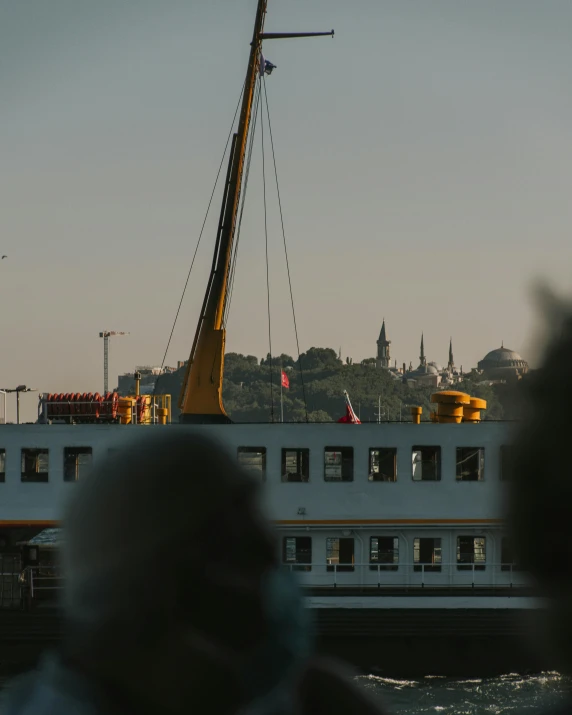 a large boat floating on top of a body of water, by Attila Meszlenyi, istanbul, people walking around, uncropped, a handsome