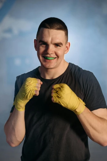 a man in a black shirt and yellow boxing gloves, a colorized photo, featured on reddit, an orc smiling into the camera, julian ope, ben shapiro, white bandage tape on fists