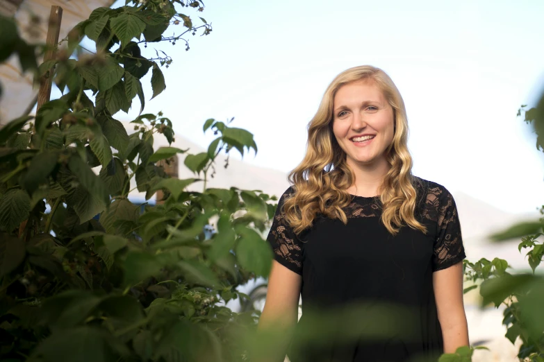 a woman in a black dress standing in a garden, a portrait, unsplash, happening, erin moriarty, yearbook photo, scientific photo, smiling