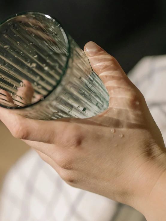 a close up of a person holding a glass, inspired by Elsa Bleda, waking up, crying and reaching with her arm, hydration, transparent corrugated glass