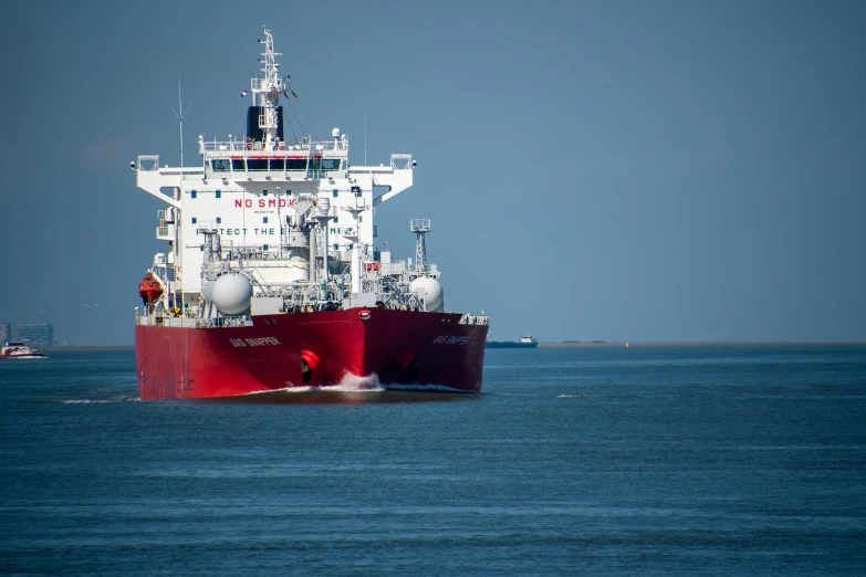 a large red boat floating on top of a body of water, ship at sea