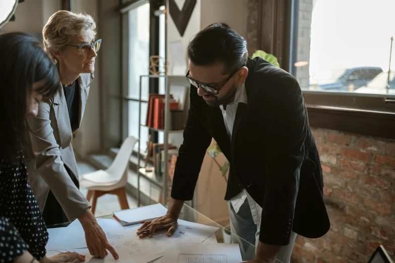 a group of people standing around a table, wearing a suit and glasses, top selection on unsplash, architectural plans, 2 people