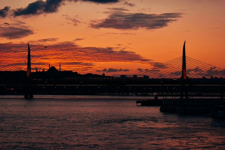 a bridge over a body of water at sunset, by Tamas Galambos, pexels contest winner, hurufiyya, istanbul, subtitles, red and orange glow, helsinki