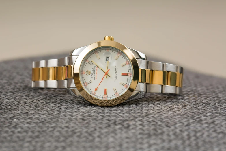 a close up of a watch on a table, by Alexander Fedosav, shiny silver with gold trim, thumbnail, white and orange, rolex