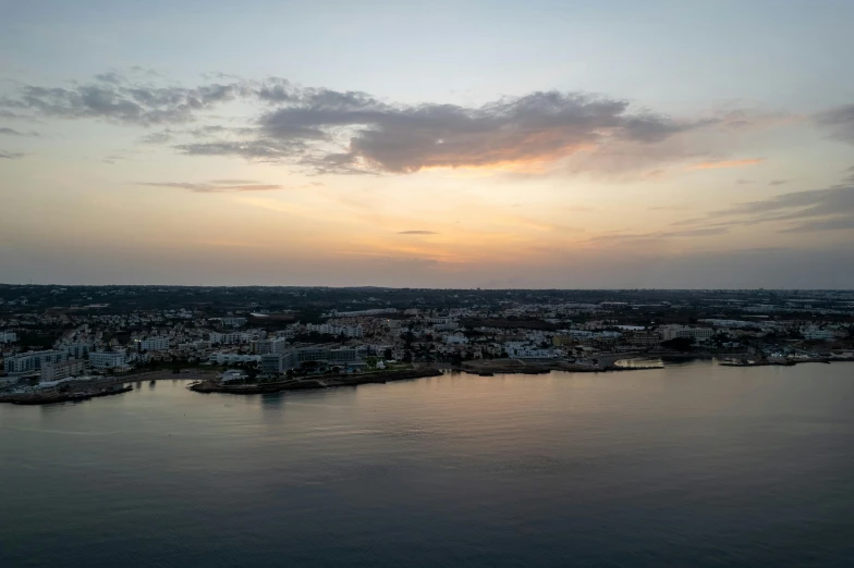 a large body of water next to a city, by Carey Morris, pexels contest winner, cloudy sunset, jamaica, alexandria\'s genesis, aerial footage