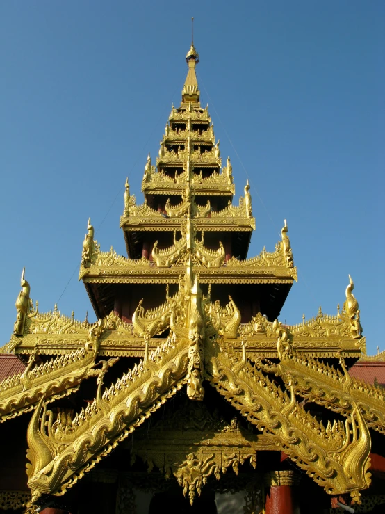 a golden building with a blue sky in the background, in front of a temple, symmetrical crown, slide show, myanmar