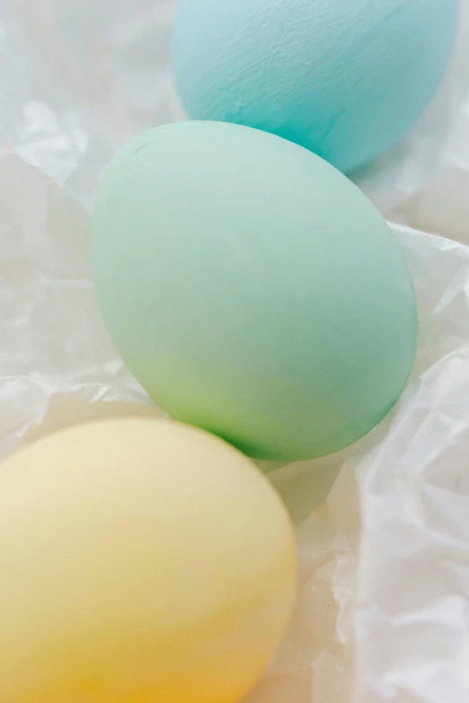 three eggs sitting next to each other on a piece of paper, a pastel, two tone dye, up-close, with celadon glaze, color photo