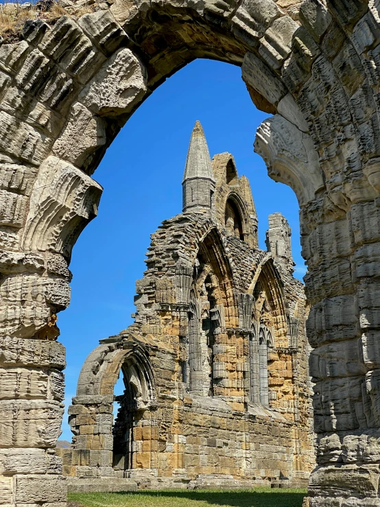 an arch in a stone building with a blue sky in the background, by Kev Walker, pexels contest winner, romanesque, asymmetrical spires, coastline, yorkshire, slide show