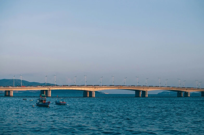 a boat in a body of water with a bridge in the background, by Jang Seung-eop, pexels contest winner, sōsaku hanga, turbines, guwahati, seaview, listing image