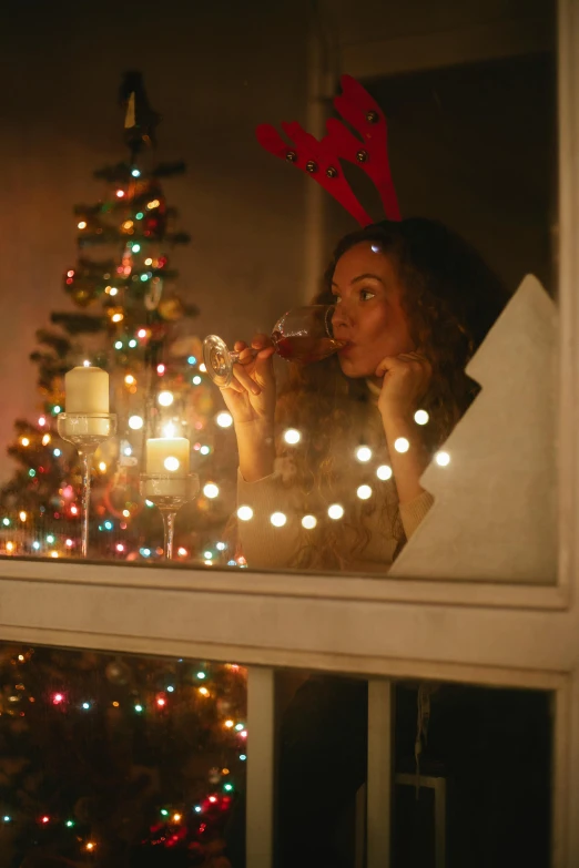 a woman drinking a glass of wine in front of a christmas tree, lights are on in the windows, light show, windowsill, profile image