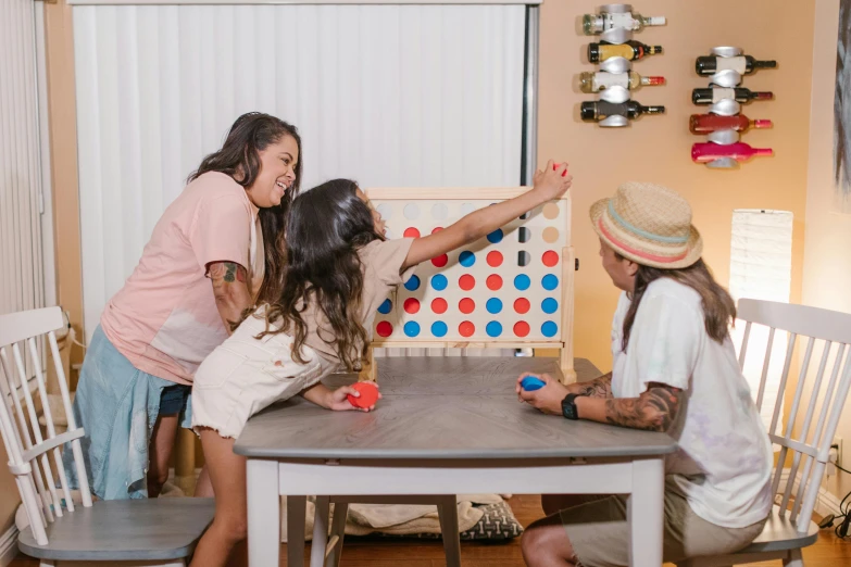 a group of people sitting around a table playing a game, on a wooden table