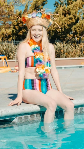 a woman sitting on the edge of a swimming pool, a colorized photo, inspired by Lisa Frank, unsplash, full costume, dressed in a top and shorts, outfit photo