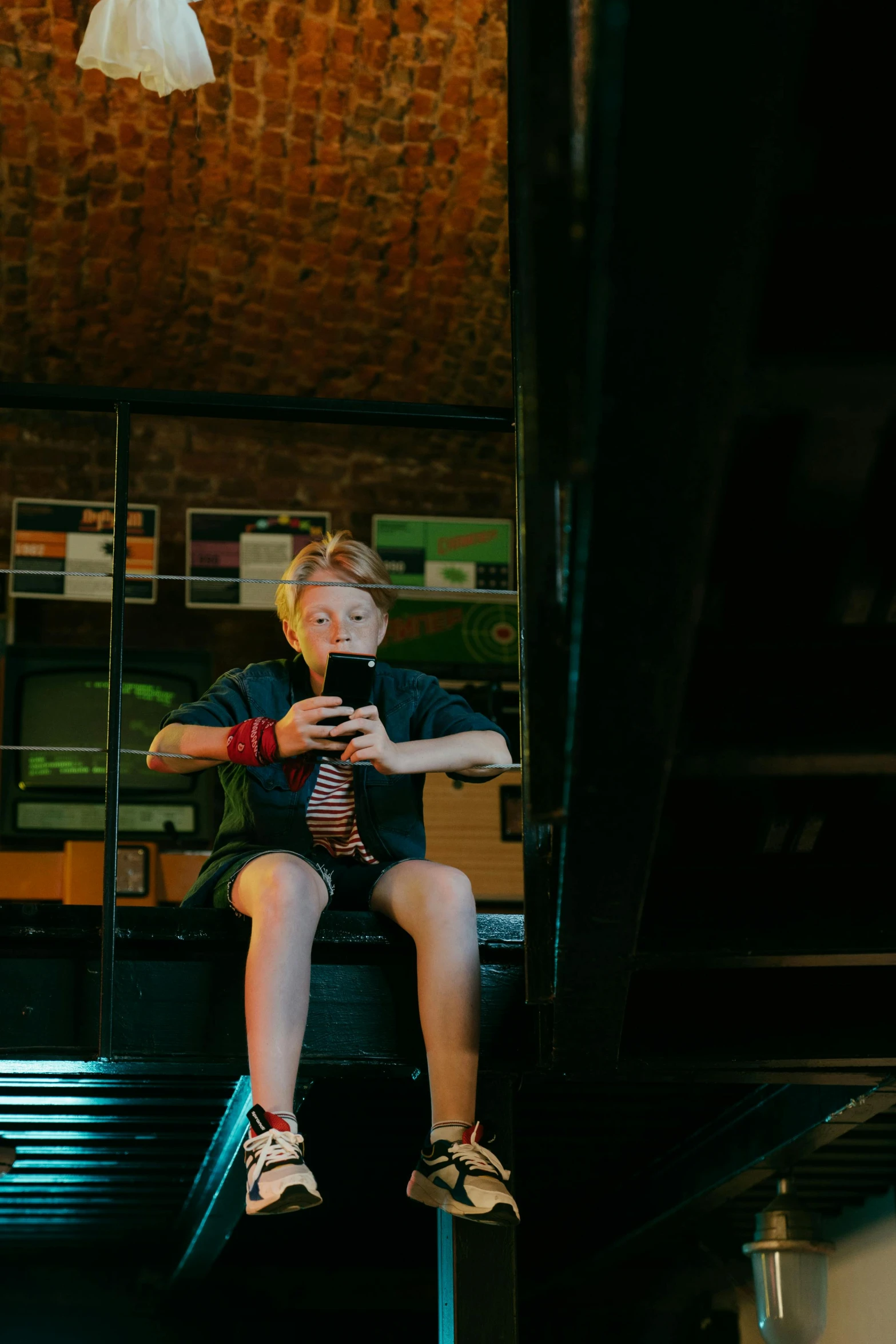 a person sitting on a chair in a room, reflection of phone in visor, red haired teen boy, low light museum, lachlan bailey