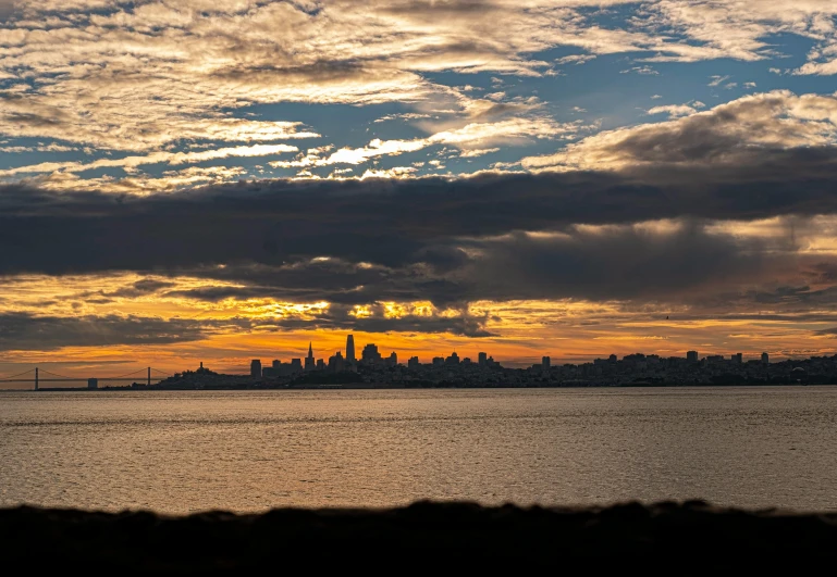 a large body of water with a city in the background, by Joseph Severn, pexels contest winner, sunset with cloudy skies, bay area, 2 0 2 2 photo, fan favorite