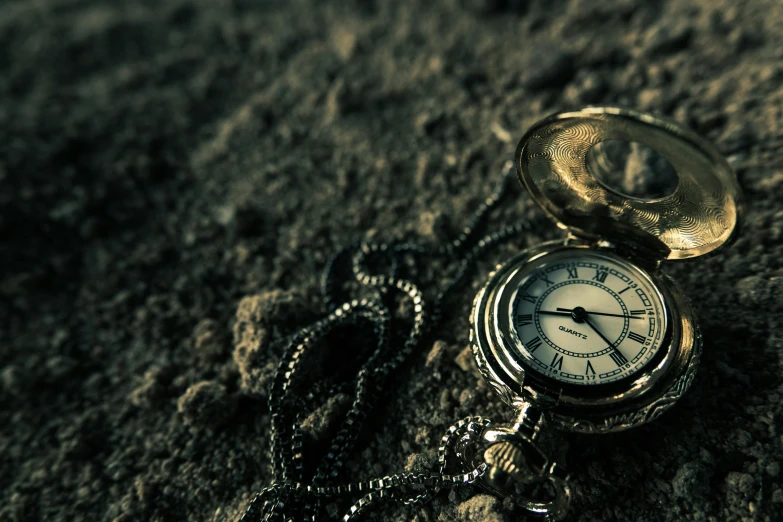 a close up of a pocket watch on a rock, an album cover, unsplash, vanitas, background image, deserted sand, dark and grungy, an intricate