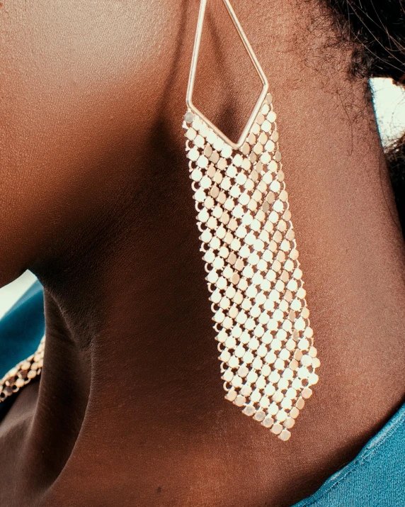 a close up of a person wearing a pair of earrings, inspired by Theo Constanté, hurufiyya, mesh wire, thumbnail, metallic torso, detailed product shot
