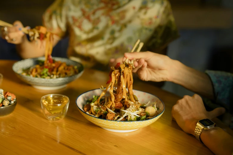 a group of people sitting at a table eating food, on a wooden plate