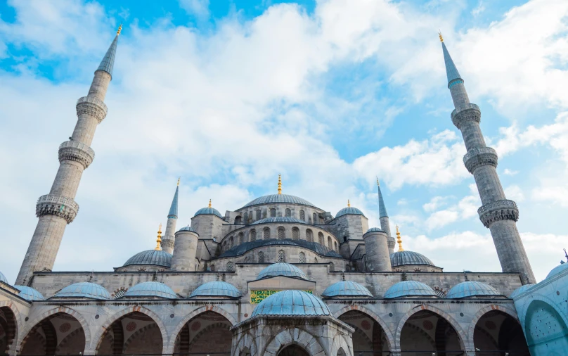 a group of people standing in front of a building, a colorized photo, pexels contest winner, hurufiyya, black domes and spires, turkey, blue, 🚿🗝📝