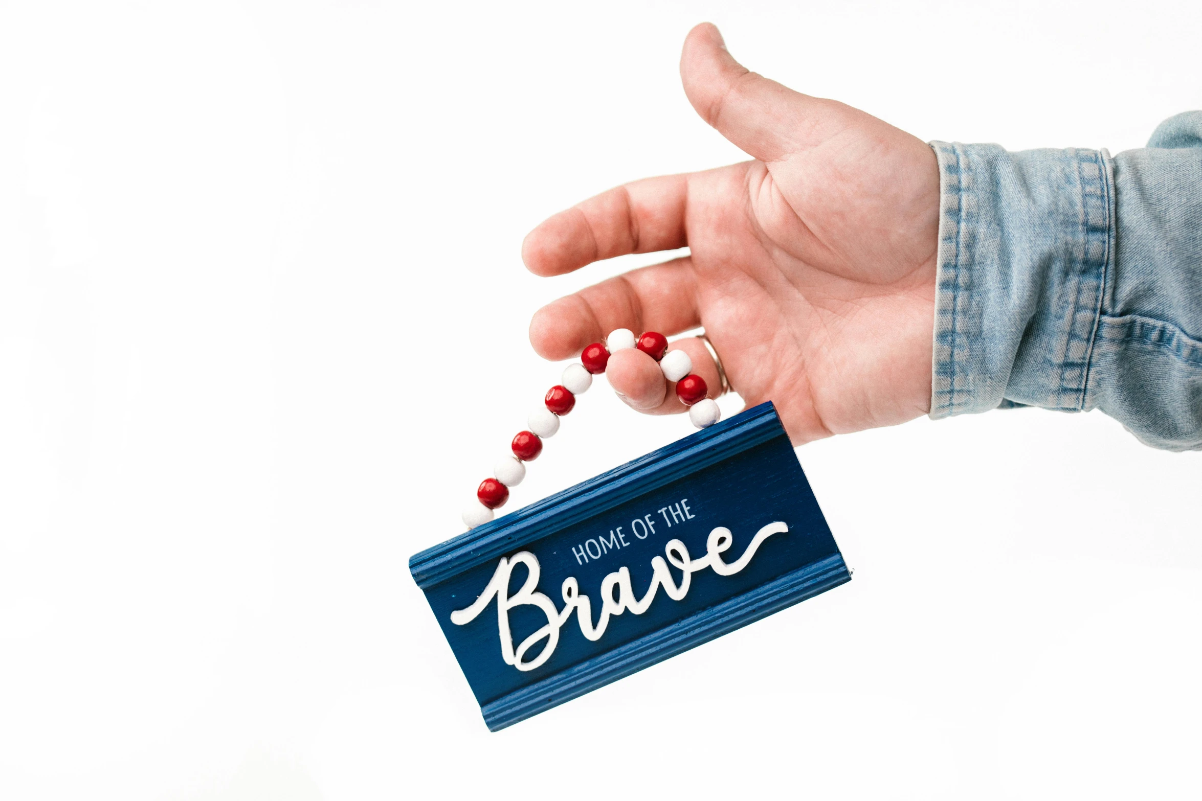 a person holding a sign that says home of the brave, unsplash, ornament, made of lollypops, detailed product shot, front view