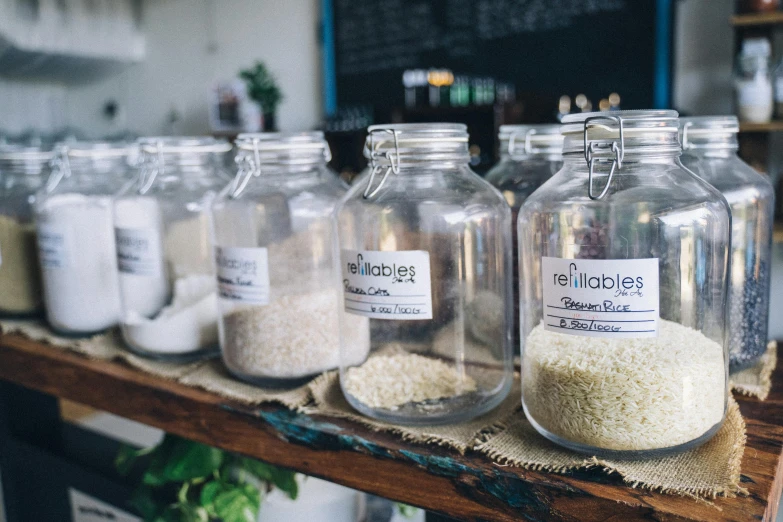 a row of jars filled with rice sitting on top of a wooden shelf, pexels, labels, pebbles, sustainable, rembranlt