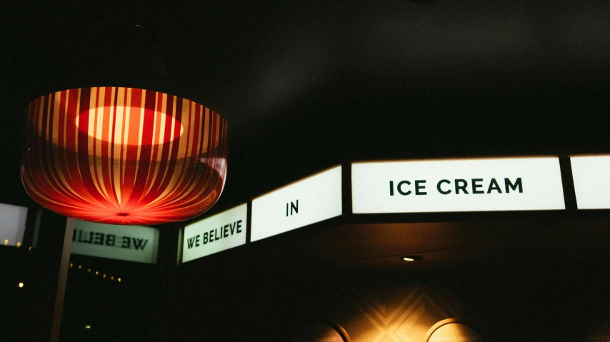 a couple of signs that are on the side of a building, inspired by roger deakins, unsplash, incoherents, ice cream, lights on ceiling, indoor picture, caulfield