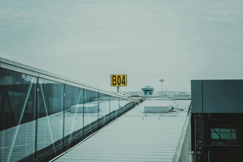 a yellow sign sitting on the side of a building, a picture, by Thomas Bock, pexels contest winner, in future airport rooftop, sky bridges, uniform off - white sky, runway