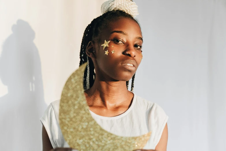 a close up of a person holding a gold moon, inspired by Ras Akyem, trending on pexels, afrofuturism, wearing a dress made of stars, cardboard cutout, black teenage girl, looking towards camera