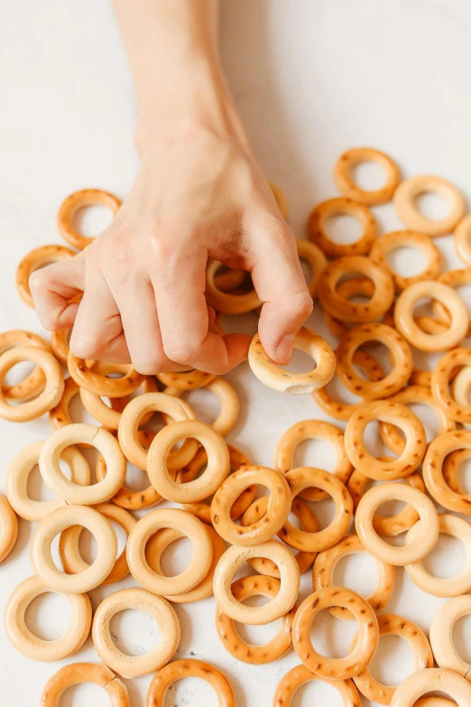 a person grabbing a pretzel out of a pile of pretzels, process art, made of swiss cheese wheels, rings, emily rajtkowski, evenly spaced