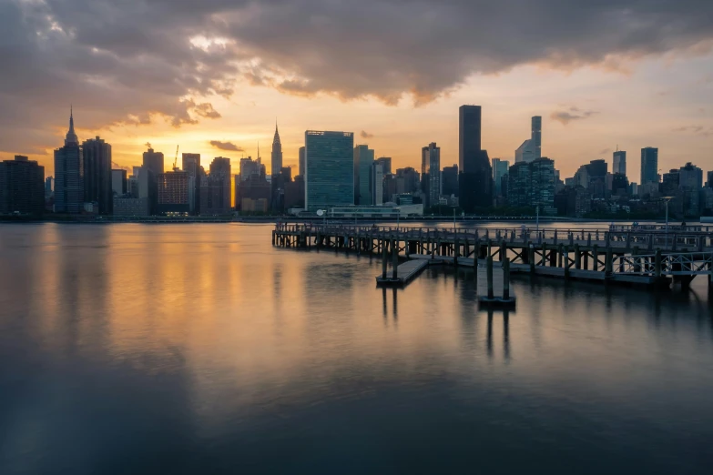 a large body of water with a city in the background, a picture, by Jason Benjamin, unsplash contest winner, tonalism, golden hour 8k, city docks, new york skyline, overcast day