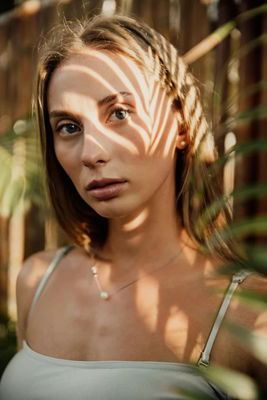 a woman standing in front of a wooden fence, a portrait, inspired by Elsa Bleda, trending on pexels, renaissance, sun lighting from above, in a jungle, tanned beauty portrait, portrait sophie mudd