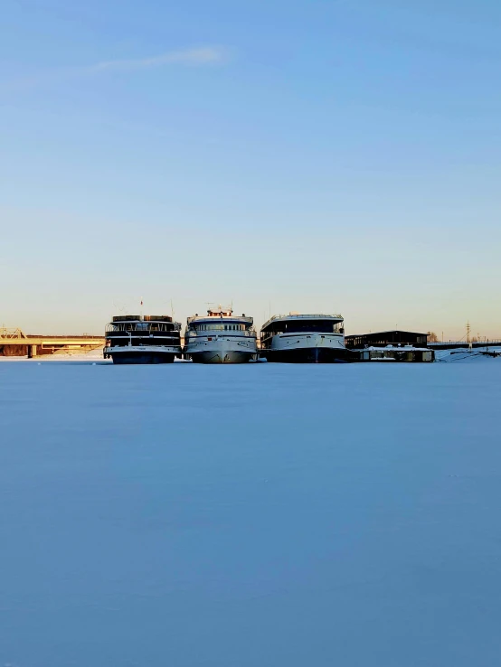 a number of boats on a body of water, covered in snow, neo norilsk, thumbnail, high quality picture