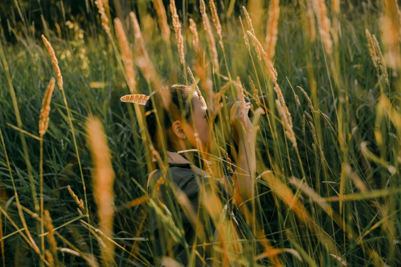 a person standing in a field of tall grass, pexels contest winner, hunting, fascinated, afternoon lighting, biophilia mood