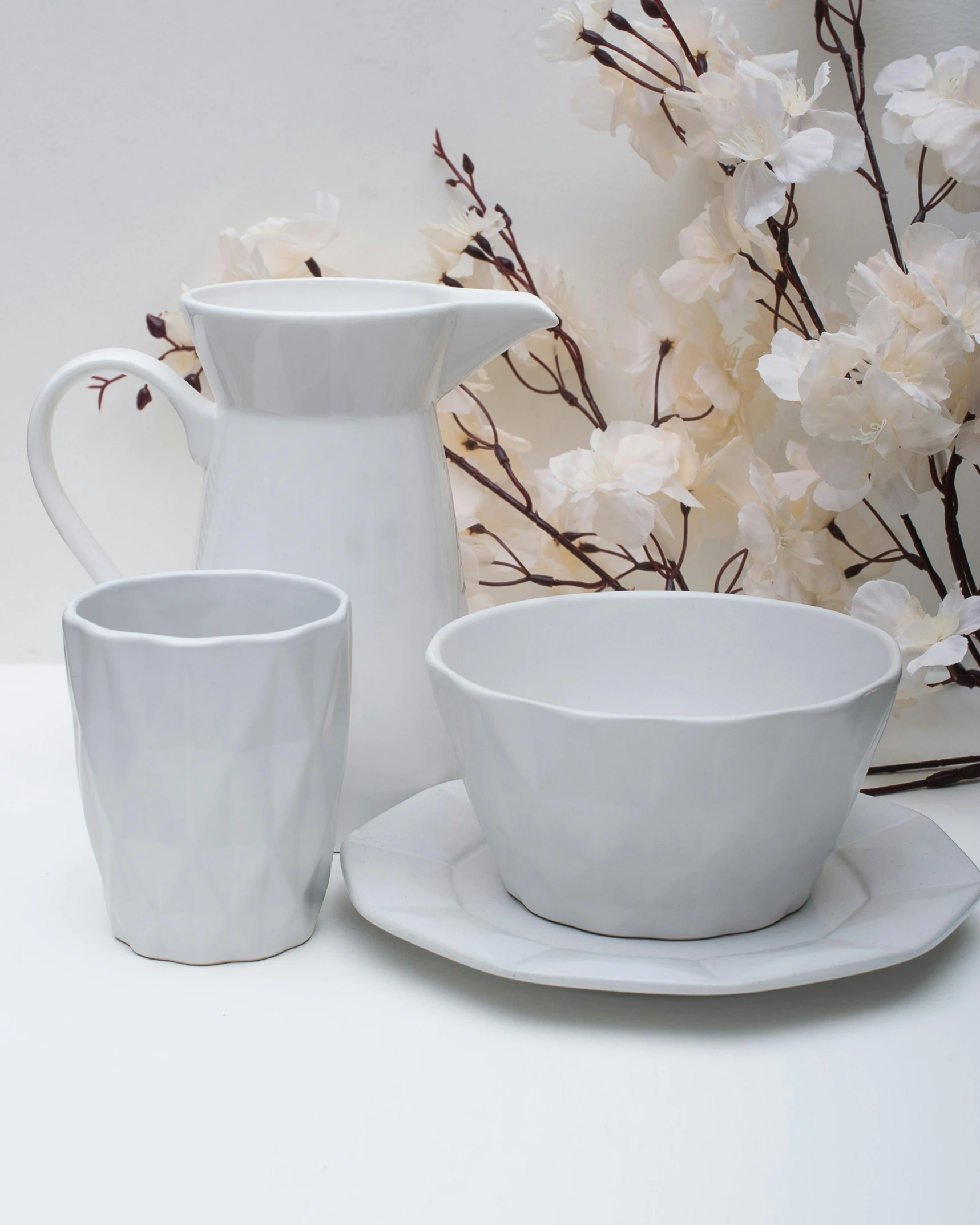 a white pitcher sitting next to a cup and saucer, inspired by Lewis Henry Meakin, minimalism, large polygons, light grey, wavy, various styles