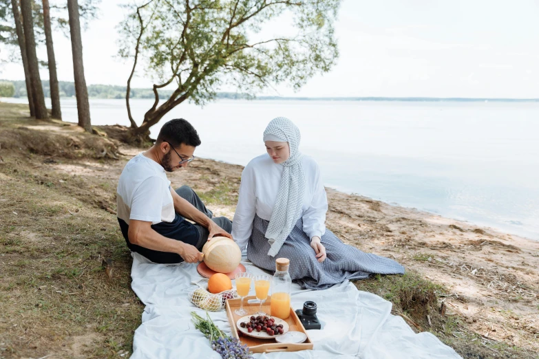 a man and a woman are having a picnic by the water, pexels contest winner, hurufiyya, white hijab, healthy, on a white table, focus on full - body