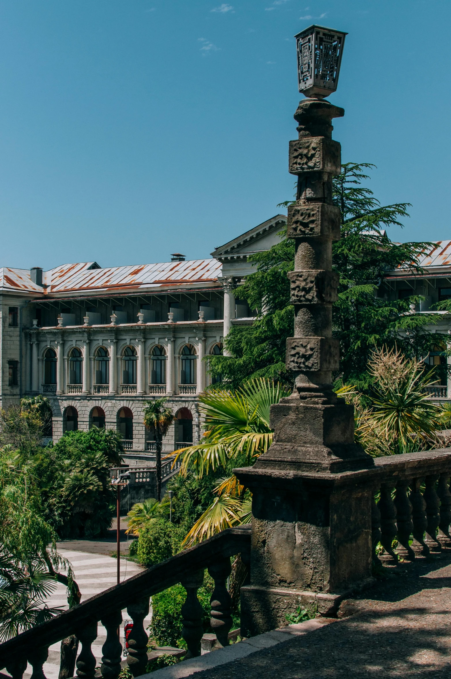 a street light sitting on the side of a road, a statue, inspired by Luis Paret y Alcazar, quito school, huge mansion, archways made of lush greenery, gothic library, staggered terraces
