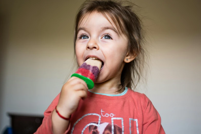 a little girl holding a popsicle in her mouth, by Matthias Stom, pexels contest winner, wearing a melon, raspberry, ellie (last of us), homemade