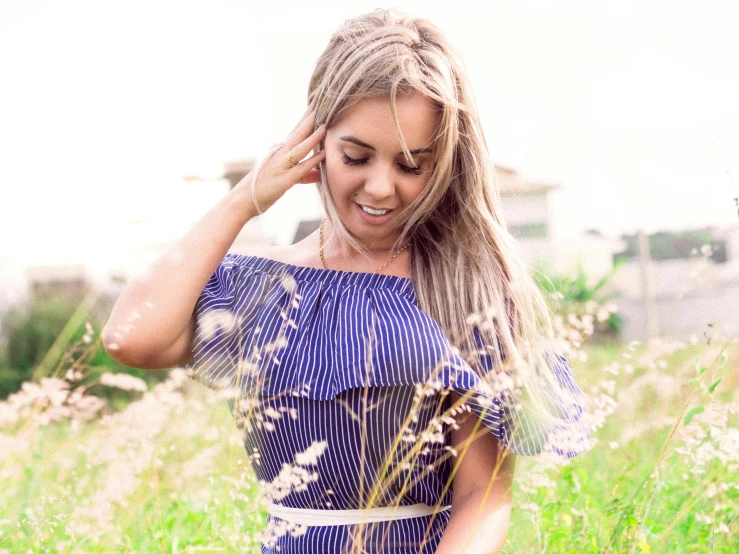 a woman standing in a field of tall grass, pexels contest winner, a gorgeous blonde, stripes, lorena avarez, wearing a blue dress