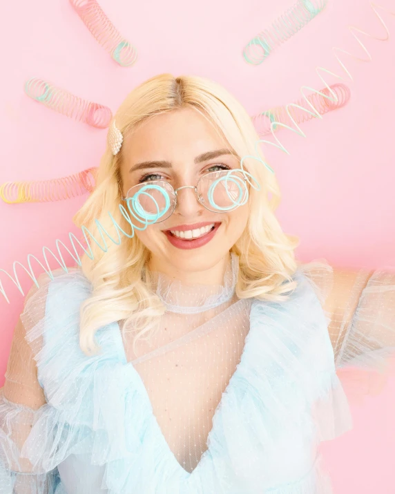 a woman in a blue dress holding two lollipop lollipop lollipop lollipop lollipop lollipop lolli, a polaroid photo, by Juliette Wytsman, trending on pexels, happening, light pink hair, transparent glasses, portrait of anya taylor-joy, happily smiling at the camera