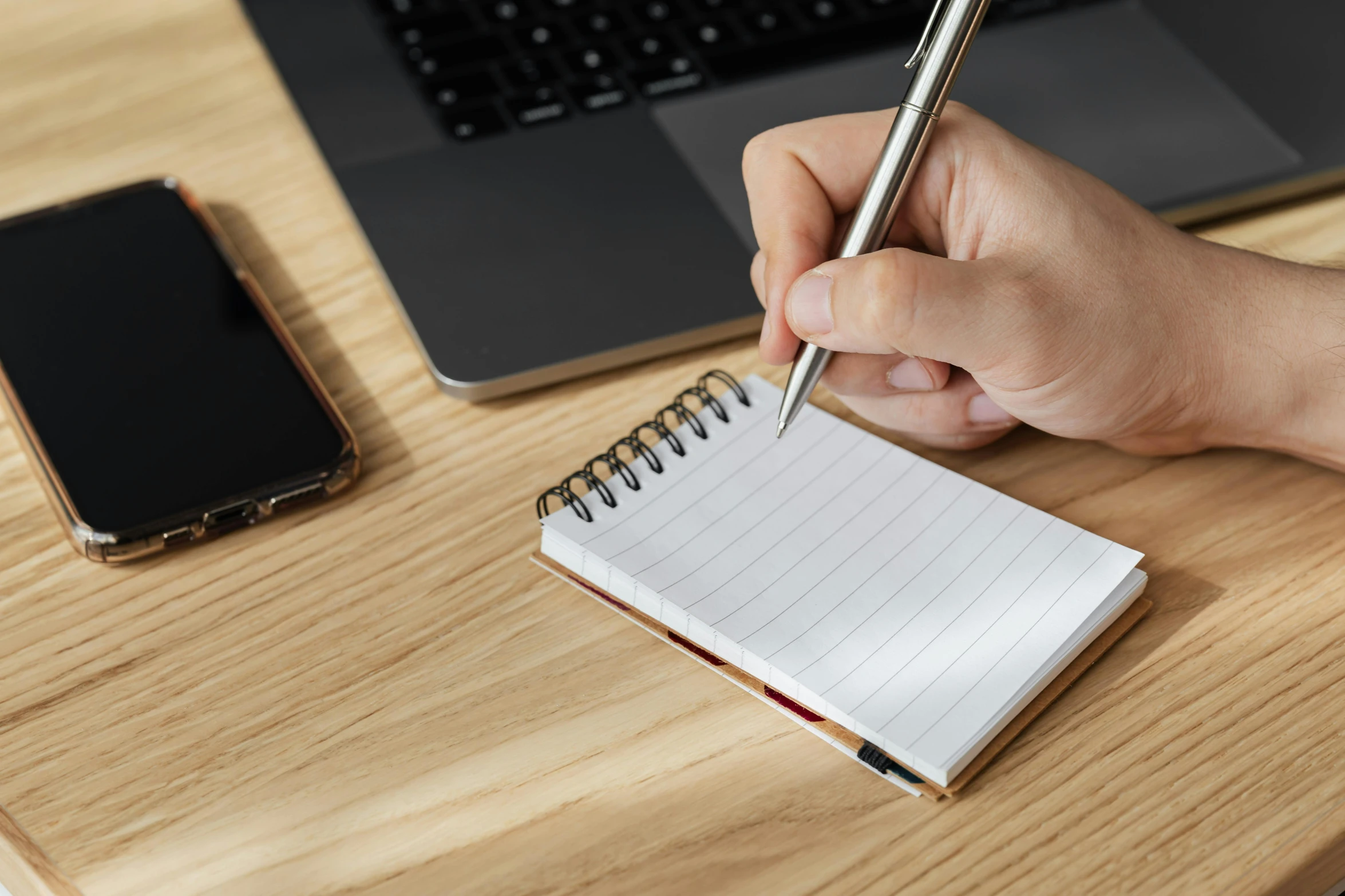 a person writing on a notepad next to a laptop, trending on pexels, essence, te pae, background image, leaked image