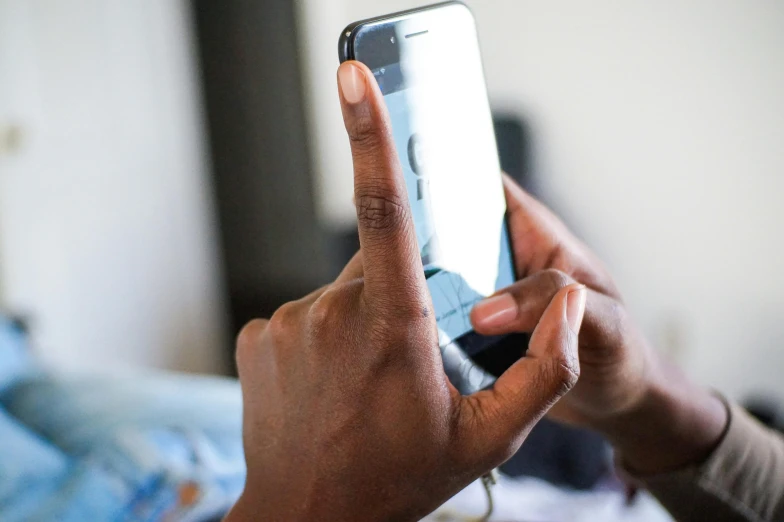 a close up of a person holding a cell phone, a photo, emmanuel shiru, someone in home sits in bed, profile image, finger