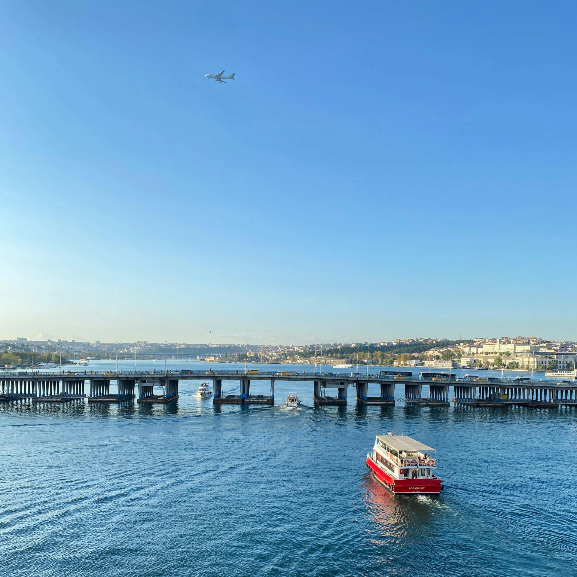 a boat on a body of water near a bridge, by Niyazi Selimoglu, pexels contest winner, hurufiyya, flying emergency vehicles, clear blue skies, manly, olafur eliasson