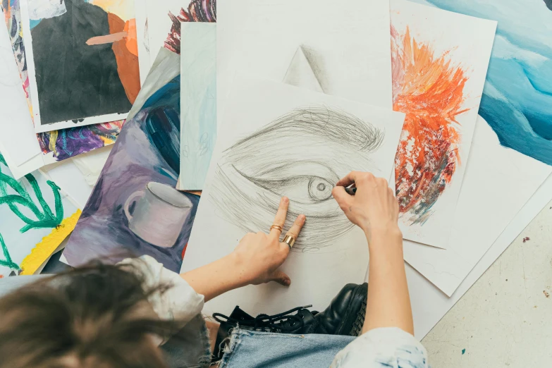 a woman is drawing on a piece of paper, inspired by artist, trending on pexels, academic art, visionary painting, top down drawing, ilustration, painting on a canvas