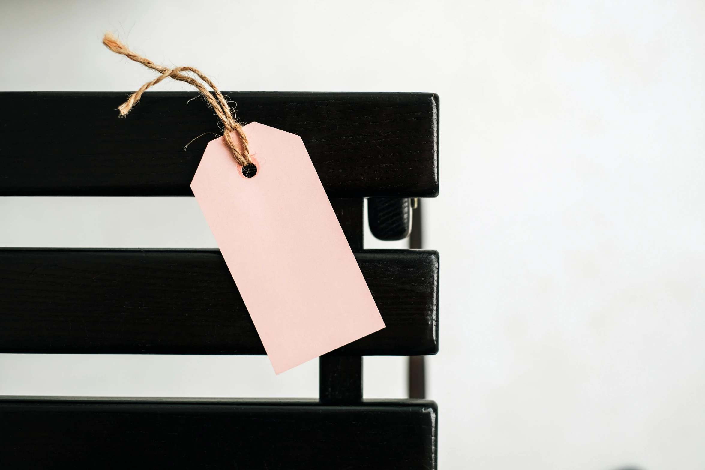 a pink tag sitting on top of a wooden bench, pexels contest winner, private press, black chair, on a white background, profile image, no - text no - logo