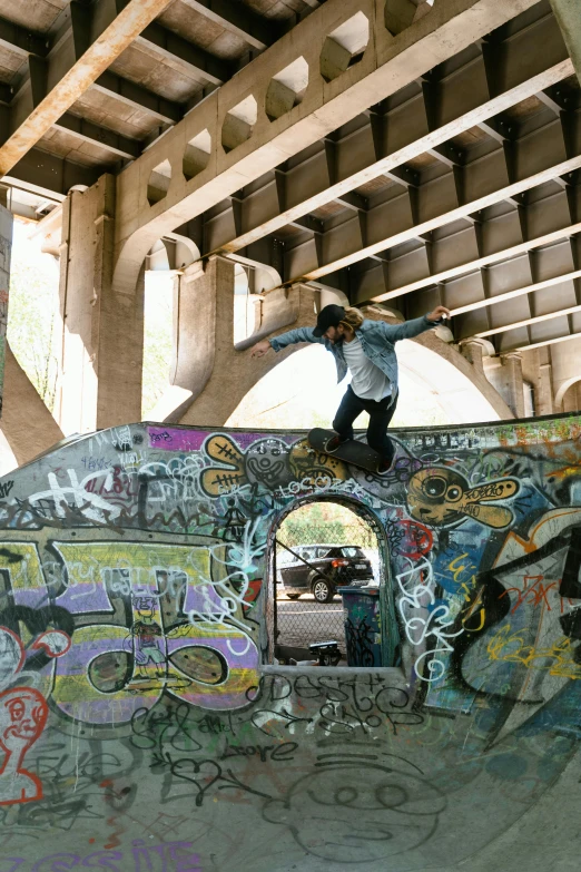 a man riding a skateboard up the side of a ramp, graffiti, rock arches, under bridge, exposed inner structure, vendors