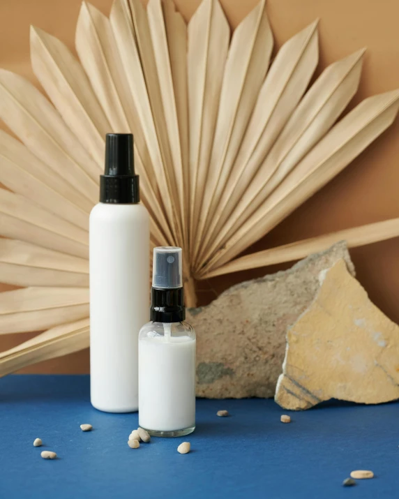 a bottle of lotion sitting on top of a blue table, a still life, inspired by Agnes Martin, unsplash, renaissance, two organic looking towers, sand mists, ivory and black marble, fan favorite