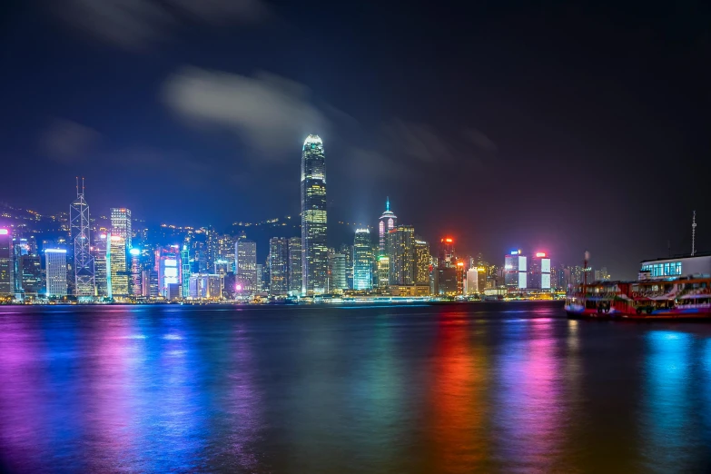 the city skyline is lit up at night, by Patrick Ching, pexels contest winner, colorful lights, harbour, distant mountains lights photo, fan favorite