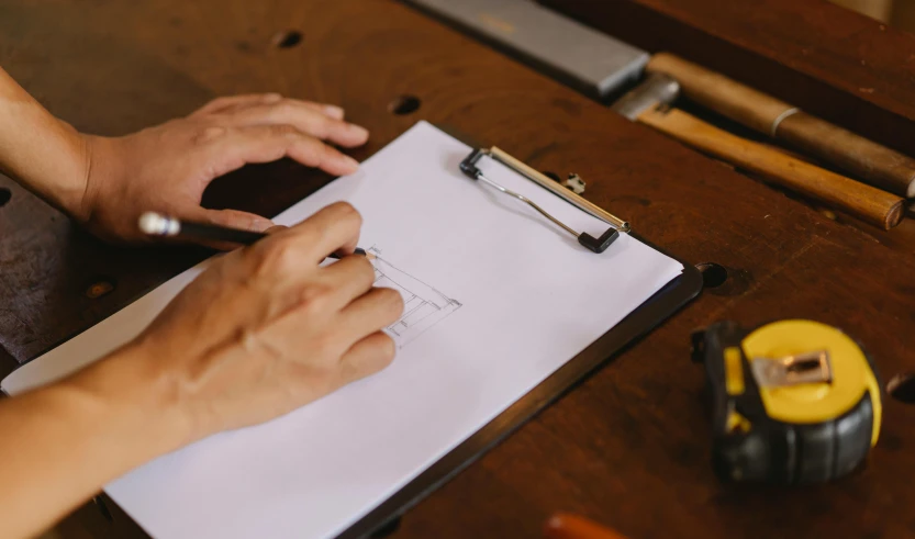 a close up of a person writing on a piece of paper, a drawing, by Matthias Stom, pexels contest winner, arbeitsrat für kunst, carpenter, 9 9 designs, thumbnail, clipboard