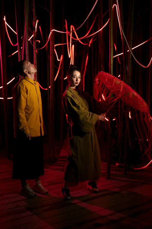 a couple of people that are standing in the dark, gutai group, red magic surrounds her, lianas, with neon lighting, zeen chin and farel dalrymple